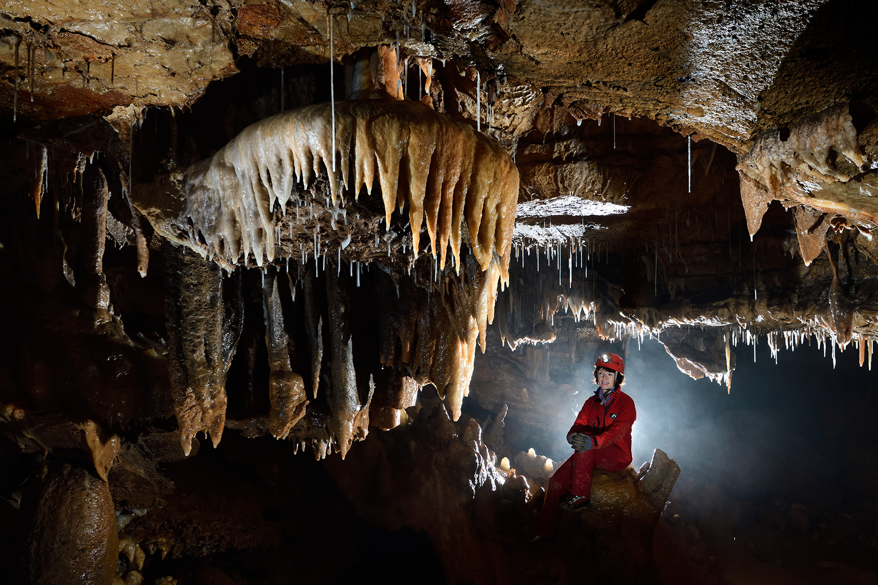 La Combe aux Prêtres - Réseau nord : spéléo  regardant un disque orné de stalactites